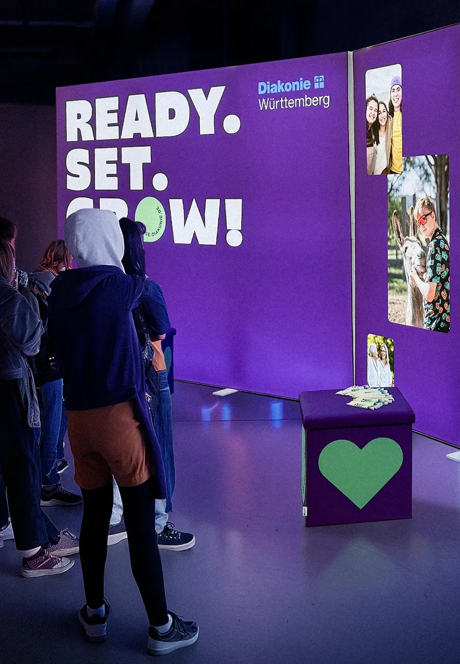 Menschengruppe vor Messestand der Diakonie