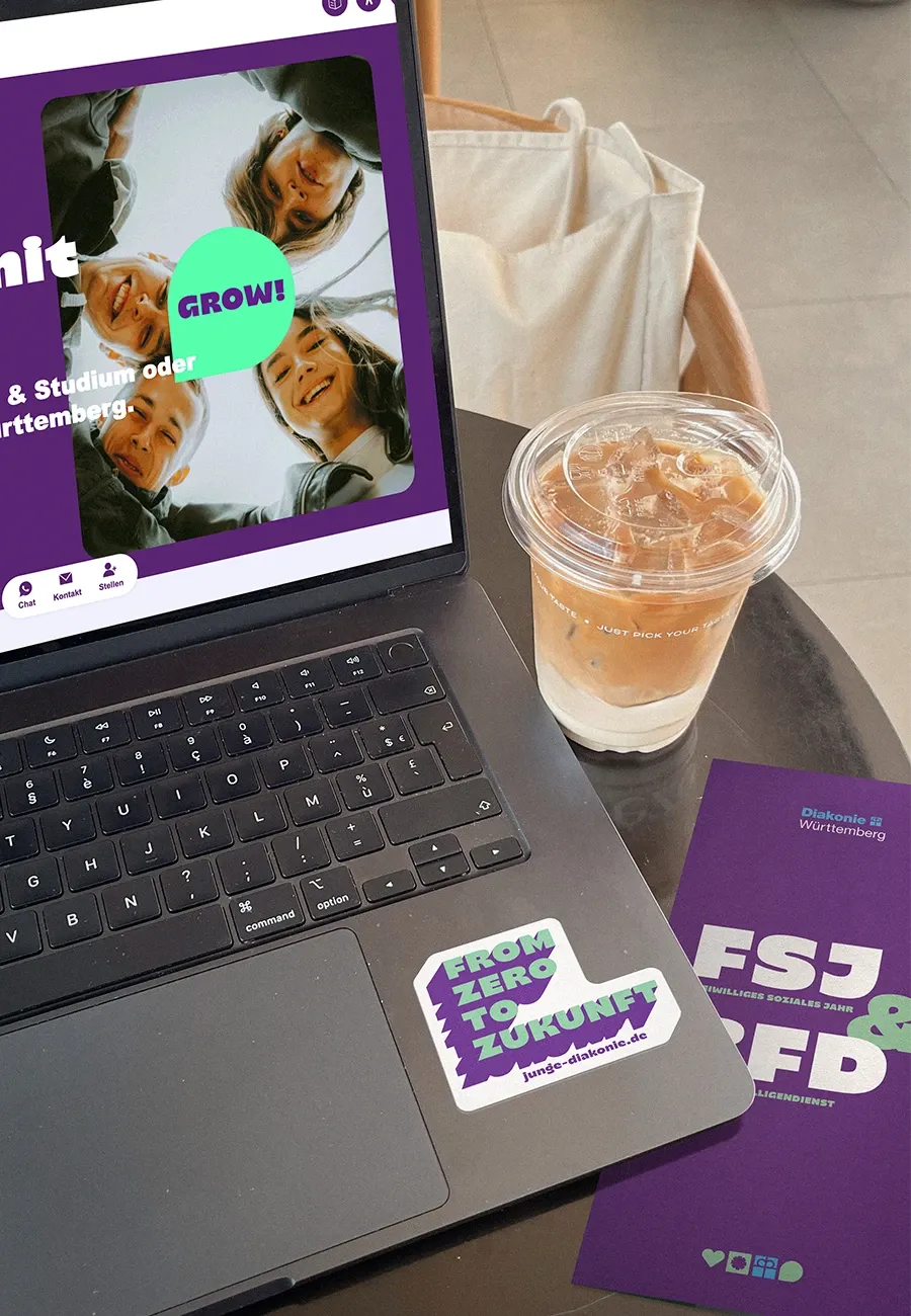 Laptop mit Sticker und Diakonie Website geöffnet daneben liegt ein Flyer 